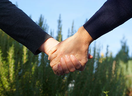 Hand in Hand, Hnde und Unterarm mit blauem Pulli, oben blauer Himmel